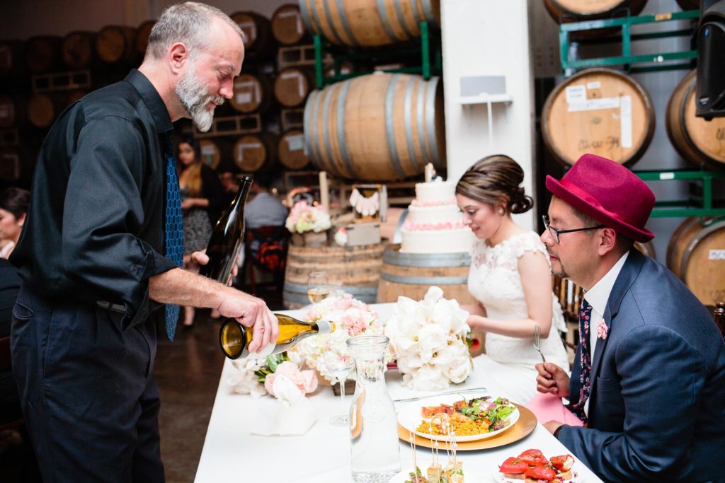 Ñora staff pouring wine for a wedding couple at their reception dinner.