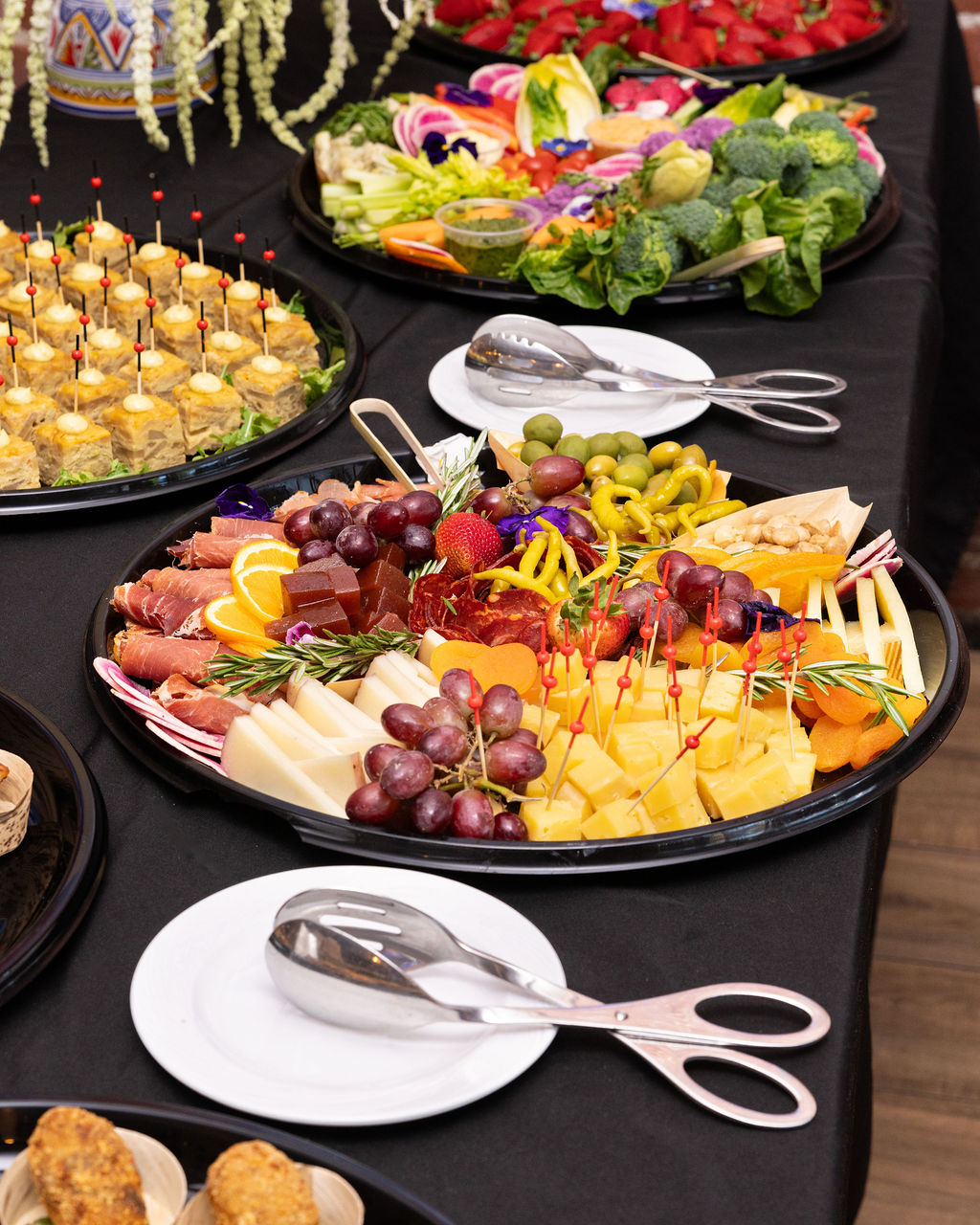 Spanish cheese and charcuterie platter with tortilla bites and fresh vegetables arranged for catering.